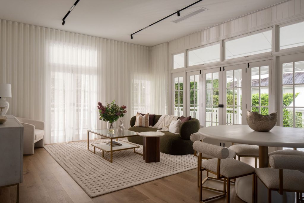 Styled open plan living and dining area with timber floors and sheer curtains