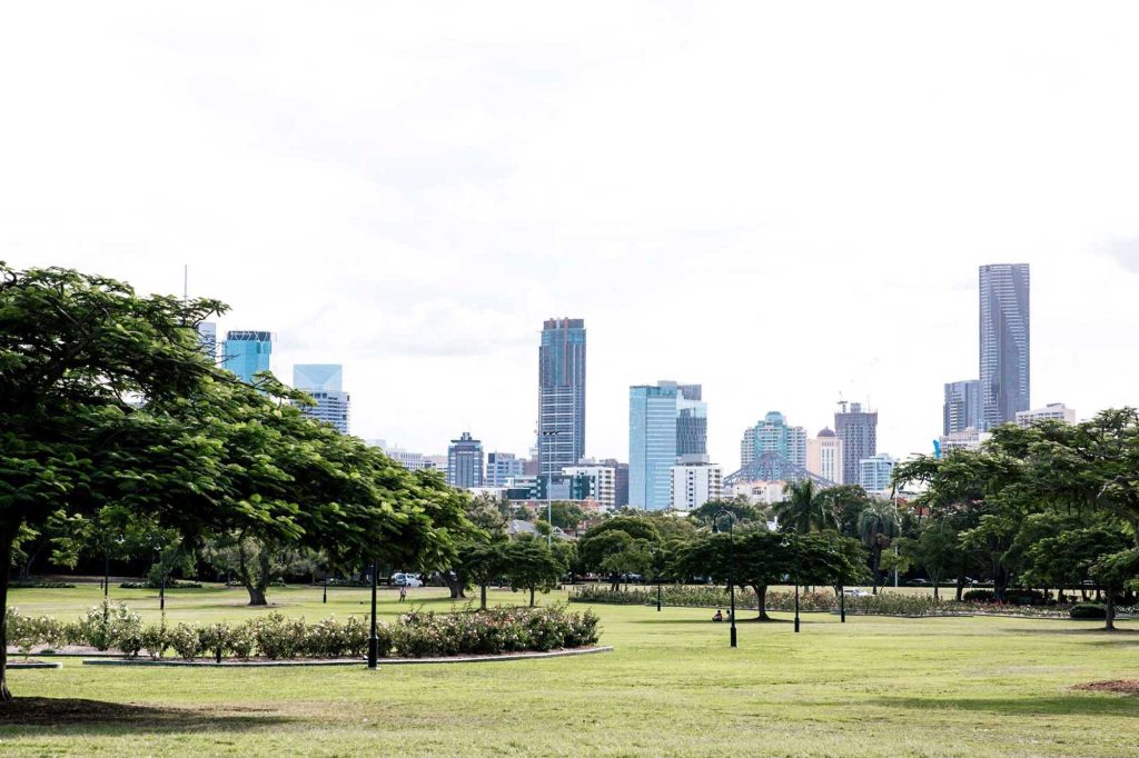 Lawns and trees in New Farm Park with the Brisbane city skyline in the distance